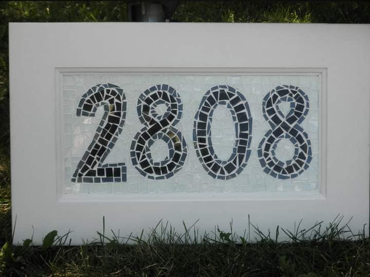 Mockzaik of house address number 2808. Dark numbers with white background resting on green grass.